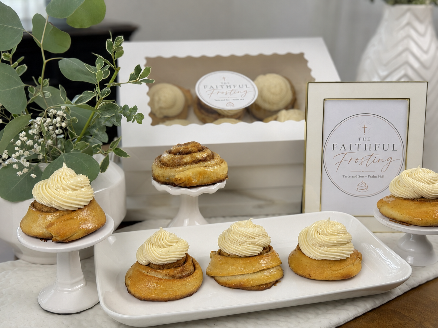Signature sourdough cinnamon rolls with piped frosting on white cake stands